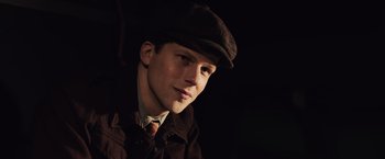 Movie still from “Resistance” (2020), directed by Jonathan Jakubowicz – A man wearing a hat and a jacket; Close Up shot, High angle