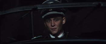 Movie still from “Resistance” (2020), directed by Jonathan Jakubowicz – A man wearing a uniform and a hat is looking out a window; Close Up shot, Low angle