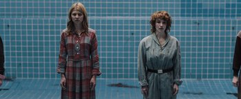 Movie still from “Resistance” (2020), directed by Jonathan Jakubowicz – Two women standing next to each other in front of a blue wall; Medium shot, High angle