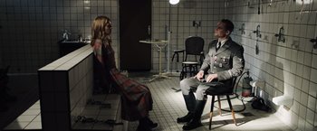 Movie still from “Resistance” (2020), directed by Jonathan Jakubowicz – A man and a woman sitting in a room; Wide shot, High angle