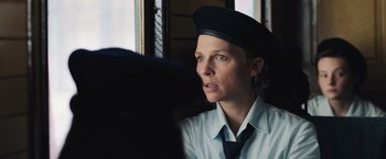 Movie still from “Resistance” (2020), directed by Jonathan Jakubowicz – A woman wearing a hat looking out of a window; Close Up shot, Over the shoulder angle