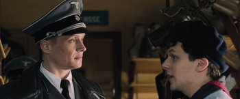 Movie still from “Resistance” (2020), directed by Jonathan Jakubowicz – A man wearing a hat and a leather jacket; Close Up shot, Over the shoulder angle