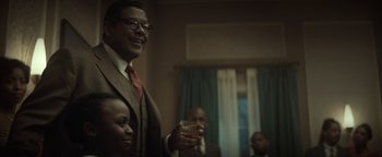 Movie still from “Respect” (2021), directed by Liesl Tommy – A group of people sitting in a living room; Medium shot, Over the shoulder angle