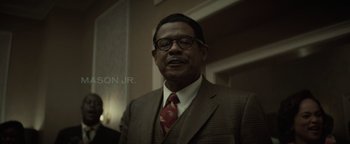 Movie still from “Respect” (2021), directed by Liesl Tommy – A man in a suit and tie standing in front of a wall; Close Up shot, Low angle