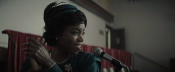 Movie still from “Respect” (2021), directed by Liesl Tommy – A woman is smiling while holding a microphone in her hand; Close Up shot, Over the shoulder angle