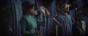 Movie still from “Respect” (2021), directed by Liesl Tommy – A woman in a green dress is singing; Medium shot, Low angle