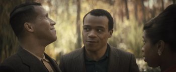 Movie still from “Respect” (2021), directed by Liesl Tommy – A man standing next to another man in front of trees; Close Up shot, Over the shoulder angle