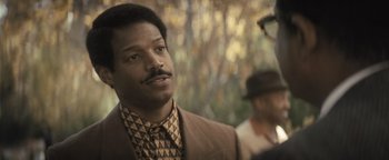 Movie still from “Respect” (2021), directed by Liesl Tommy – A man in a brown suit and a tie; Close Up shot, Over the shoulder angle