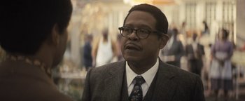 Movie still from “Respect” (2021), directed by Liesl Tommy – An older man wearing a suit and tie; Close Up shot, Over the shoulder angle
