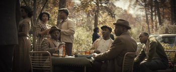 Movie still from “Respect” (2021), directed by Liesl Tommy – A group of men sitting at a table with drinks; Wide shot, High angle