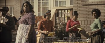 Movie still from “Respect” (2021), directed by Liesl Tommy – A group of women standing around a table; Medium shot, High angle