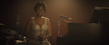 Movie still from “Respect” (2021), directed by Liesl Tommy – A woman sitting in front of a piano in front of a microphone; Medium shot, Over the shoulder angle