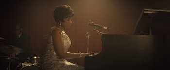Movie still from “Respect” (2021), directed by Liesl Tommy – A woman sitting at a piano in front of a microphone; Medium shot, Low angle