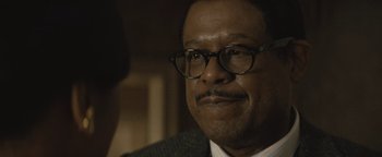 Movie still from “Respect” (2021), directed by Liesl Tommy – A person wearing glasses and a suit; Close Up shot, Over the shoulder angle