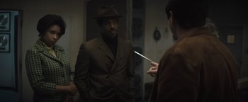 Movie still from “Respect” (2021), directed by Liesl Tommy – A man wearing a brown suit and a brown hat is looking at himself in the mirror; Medium shot, Over the shoulder angle
