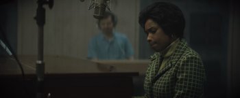 Movie still from “Respect” (2021), directed by Liesl Tommy – A woman sitting at a piano in front of a microphone; Medium shot, Over the shoulder angle