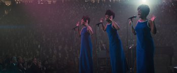 Movie still from “Respect” (2021), directed by Liesl Tommy – A couple of women singing into microphones in front of an audience; Medium shot, Low angle