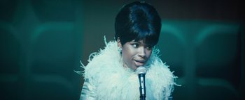 Movie still from “Respect” (2021), directed by Liesl Tommy – A woman in a white jacket is holding a microphone; Close Up shot, Low angle