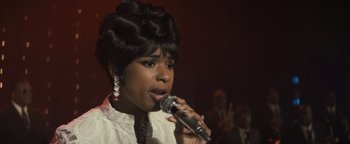 Movie still from “Respect” (2021), directed by Liesl Tommy – A woman in a white shirt is singing into a microphone; Close Up shot, Low angle