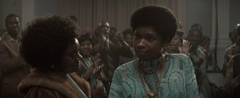 Movie still from “Respect” (2021), directed by Liesl Tommy – A group of people standing in a room; Close Up shot, Over the shoulder angle