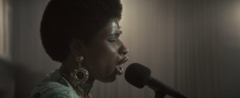 Movie still from “Respect” (2021), directed by Liesl Tommy – A woman is singing into a microphone in a room; Close Up shot, Low angle