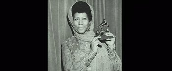 Movie still from “Respect” (2021), directed by Liesl Tommy – A black and white photo of a woman holding a gramaphone; Close Up shot, Low angle