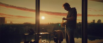 Movie still from “Retribution” (2023), directed by Nimród Antal – A man standing in front of a large window; Medium shot, Low angle