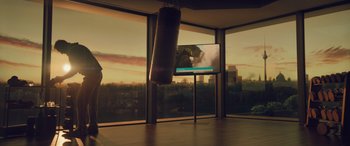 Movie still from “Retribution” (2023), directed by Nimród Antal – A boxing bag in front of a large tv screen; Extreme Wide shot, Low angle