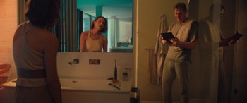 Movie still from “Retribution” (2023), directed by Nimród Antal – A woman looking in the mirror in a bathroom; Medium shot, Low angle