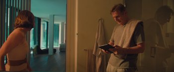 Movie still from “Retribution” (2023), directed by Nimród Antal – A man standing next to a bathroom holding an ipad; Medium shot, Low angle