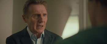 Movie still from “Retribution” (2023), directed by Nimród Antal – An older man in a gray suit is looking at the camera; Close Up shot, Over the shoulder angle