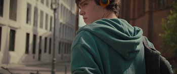 Movie still from “Retribution” (2023), directed by Nimród Antal – A young man wearing a green jacket and orange headphones; Close Up shot, Low angle