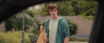 Movie still from “Retribution” (2023), directed by Nimród Antal – A young man wearing headphones while standing outside; Close Up shot, Over the shoulder angle