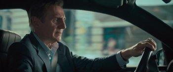 Movie still from “Retribution” (2023), directed by Nimród Antal – An older man in a suit and tie driving a car; Close Up shot, Over the shoulder angle