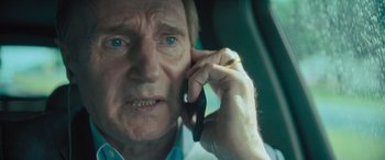 Movie still from “Retribution” (2023), directed by Nimród Antal – An older man talking on a cell phone in a car; Close Up shot, Low angle