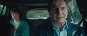 Movie still from “Retribution” (2023), directed by Nimród Antal – An older man in a suit and headphones in a car; Close Up shot, Over the shoulder angle