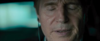 Movie still from “Retribution” (2023), directed by Nimród Antal – An older man wearing ear buds in a car; Extreme Close Up shot, Low angle