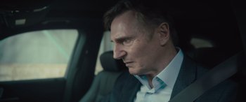 Movie still from “Retribution” (2023), directed by Nimród Antal – A person wearing a suit and tie in a car; Close Up shot, Over the shoulder angle