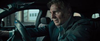 Movie still from “Retribution” (2023), directed by Nimród Antal – A man in a suit driving in a car; Close Up shot, Low angle