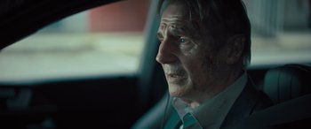 Movie still from “Retribution” (2023), directed by Nimród Antal – An older man wearing headphones in a car; Close Up shot, Over the shoulder angle