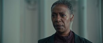 Movie still from “Retribution” (2023), directed by Nimród Antal – An older black woman wearing a black suit and white earrings; Close Up shot, Over the shoulder angle