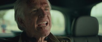 Movie still from “Retribution” (2023), directed by Nimród Antal – An older man with a bloody face in a car; Close Up shot, Low angle