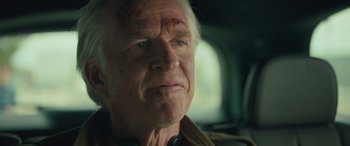 Movie still from “Retribution” (2023), directed by Nimród Antal – An older man with a bruise on his face; Close Up shot, Over the shoulder angle