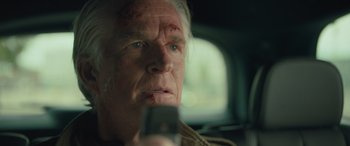 Movie still from “Retribution” (2023), directed by Nimród Antal – An older man looking at a cell phone in a car; Close Up shot, Low angle