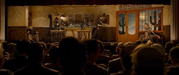 Movie still from “Revolutionary Road” (2008), directed by Sam Mendes – A group of people sitting in front of a stage; Wide shot, Over the shoulder angle