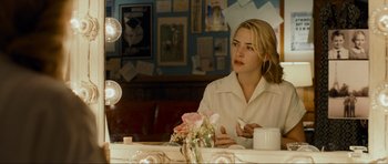 Movie still from “Revolutionary Road” (2008), directed by Sam Mendes – A woman sitting at a table in front of a vase of flowers; Close Up shot, Over the shoulder angle