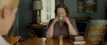 Movie still from “Revolutionary Road” (2008), directed by Sam Mendes – A woman sitting at a table with a cup in her hand; Medium shot, High angle