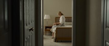 Movie still from “Revolutionary Road” (2008), directed by Sam Mendes – A woman sitting on the edge of a bed in a bedroom; Wide shot, High angle