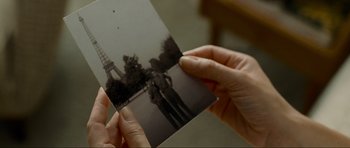 Movie still from “Revolutionary Road” (2008), directed by Sam Mendes – A person holding an old photo of a couple in front of the eiffel tower; Extreme Close Up shot, Over the shoulder angle