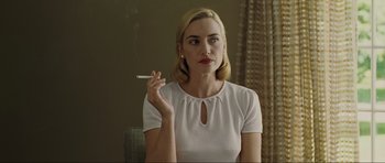 Movie still from “Revolutionary Road” (2008), directed by Sam Mendes – A woman smoking a cigarette while sitting down; Medium shot, Over the shoulder angle